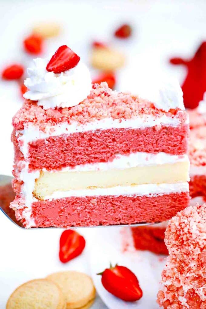 a slice of strawberry crunch cheesecake cake on a serving spatula