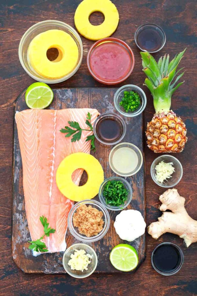 overhead shot of large salmon fillet pineapple rings chili sauce in bowls on a table