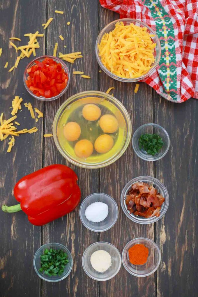 overhead shot of eggs pepper spices cheese and bacon in bowls on a table