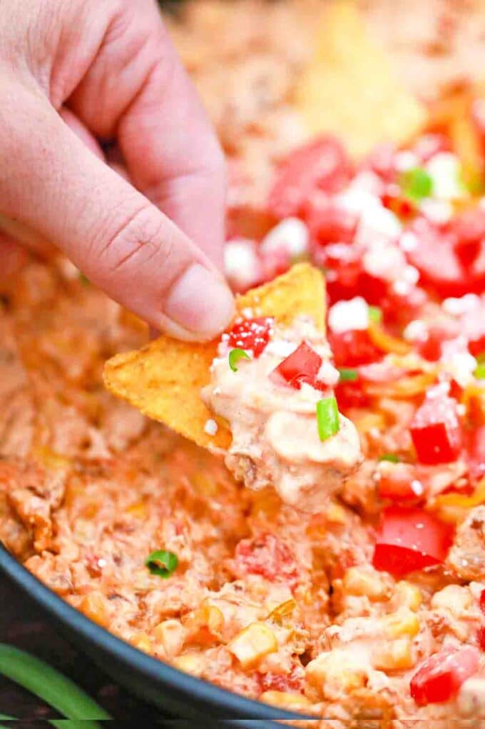dipping a corn tortilla chips in queso dip