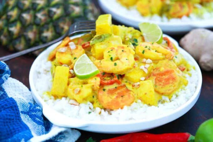 ineapple coconut shrimp curry on top of a plate with rice and pineapple in the background
