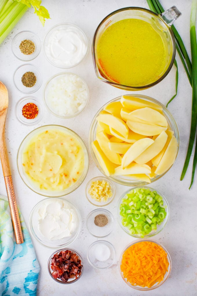 Overhead shot of Instant Pot loaded baked potato soup ingredients in bowls on a white surface.