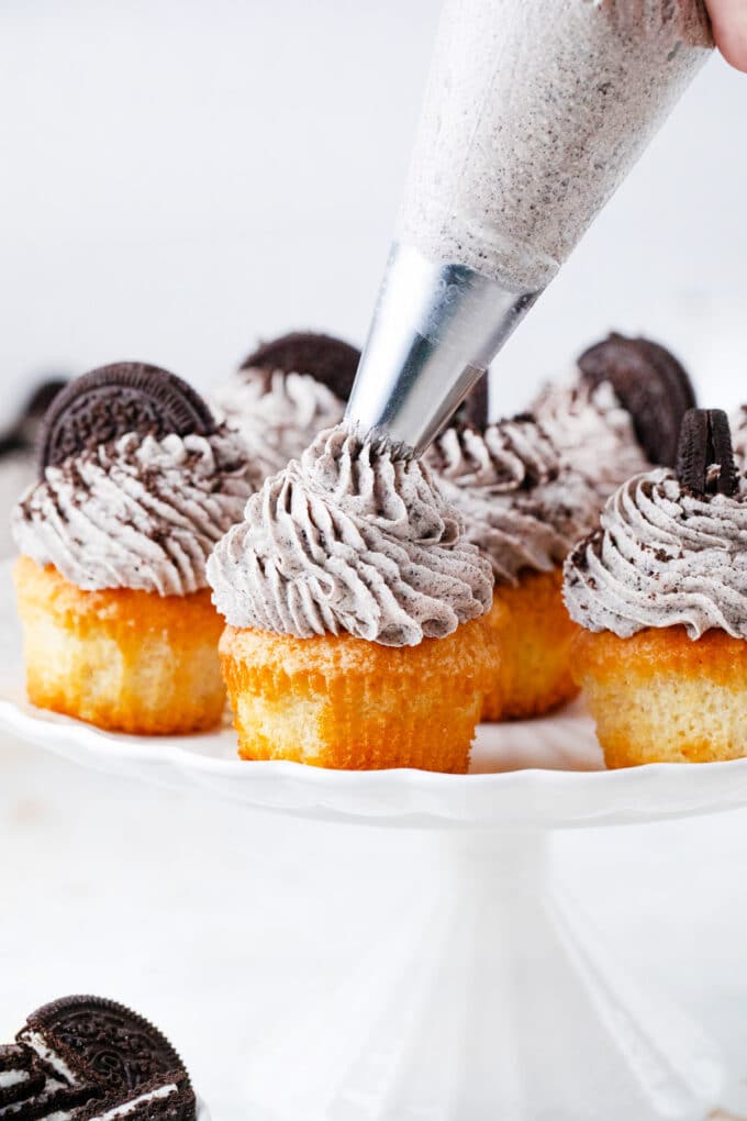 Piping Oreo buttercream onto cupcakes.
