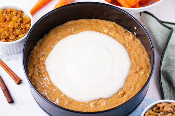 Combining carrot cake batter and cheesecake batter in a springform pan.