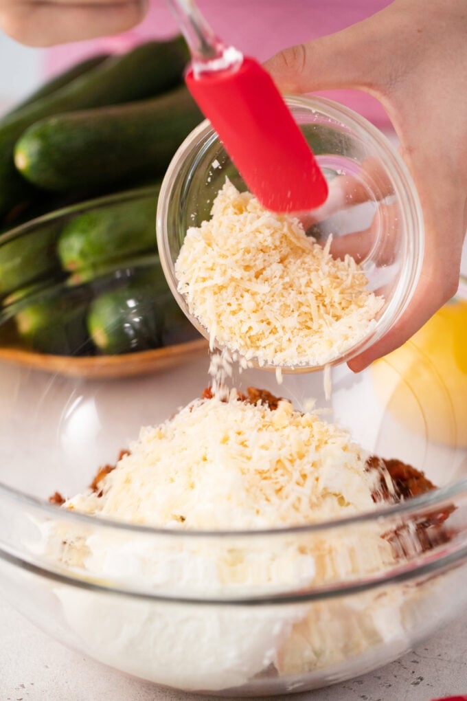 Adding shredded cheese to ground beef mixture.