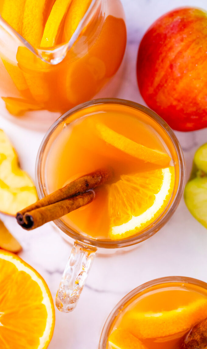 Overhead shot of a glass of apple cider with oranges.