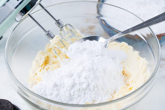 Adding powdered sugar to whisked butter.