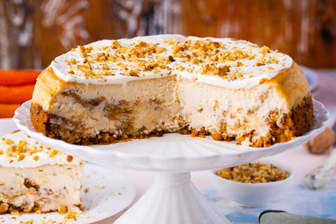 Sliced swirled carrot cake cheesecake topped with chopped walnuts.