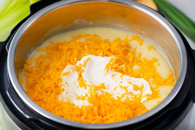 Adding cheddar cheese and sour cream to Instant Pot loaded baked potato soup.