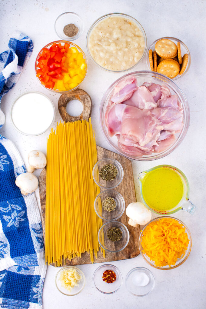 Overhead shot of chicken spaghetti casserole ingredients in bowls on a table.