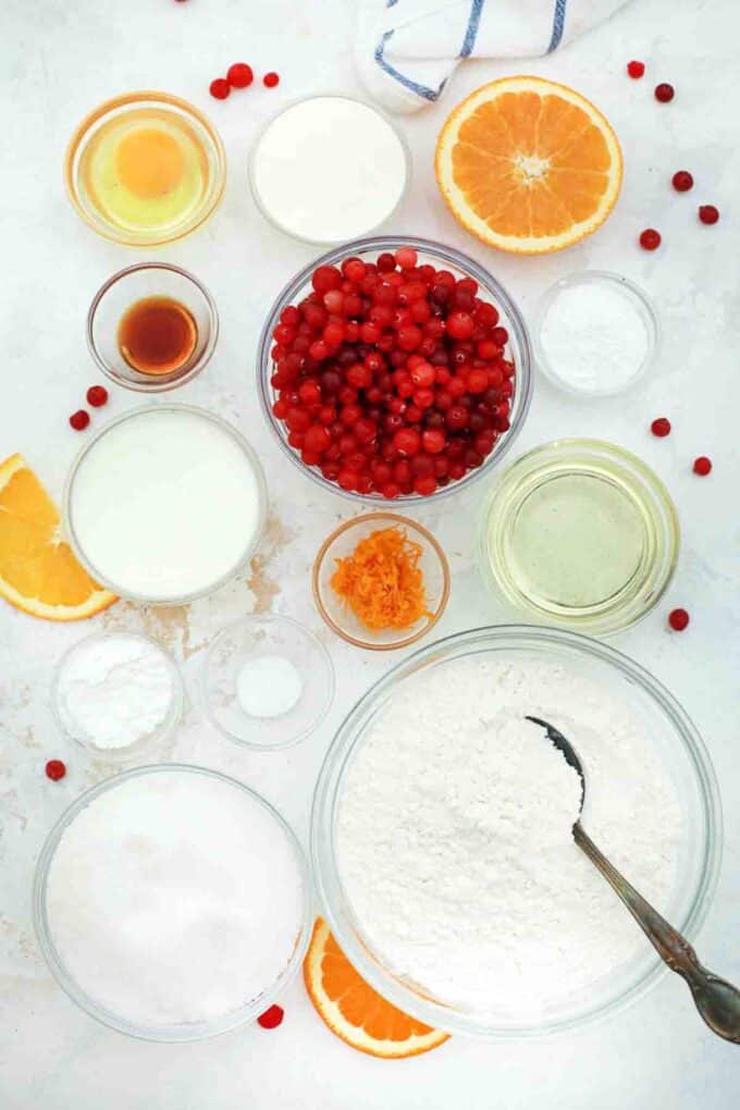 overhead shot of flour sugar cranberries orange juice zest eggs in bowls on a table