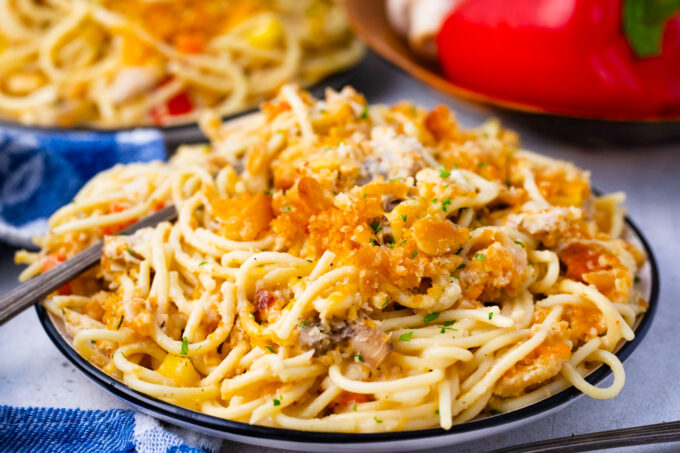 A plate of baked chicken spaghetti casserole with cheesy cracker topping.