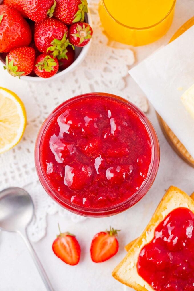 Overhead shot of a jar of homemade strawberry jam, toast, and butter.