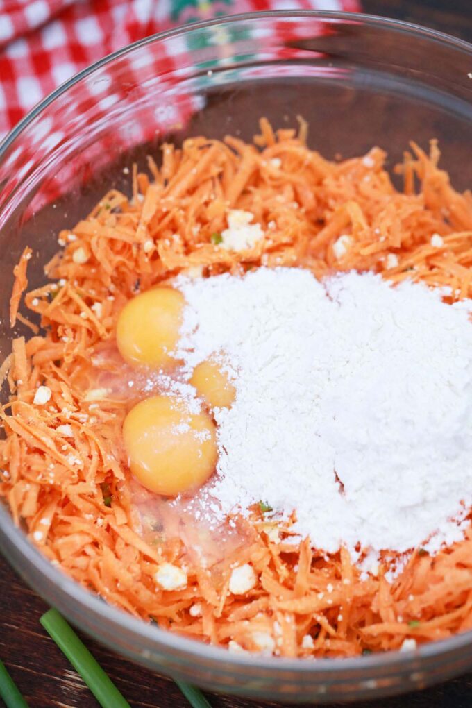 Shredded sweet potatoes, eggs, and flour in a bowl.
