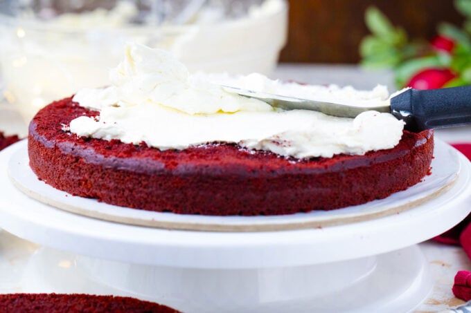 Frosting a red velvet cake layer.