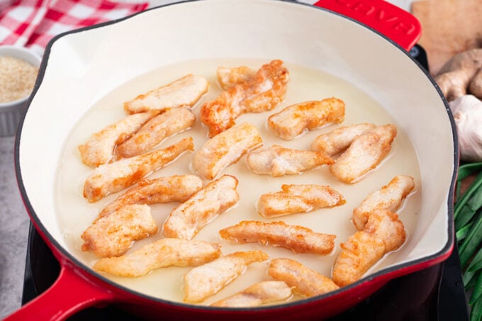 Frying chicken pieces in oil.