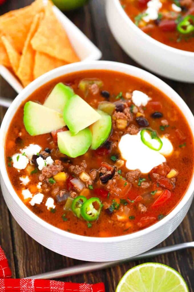 bowl of taco soup topped with cheese sour cream and avocado