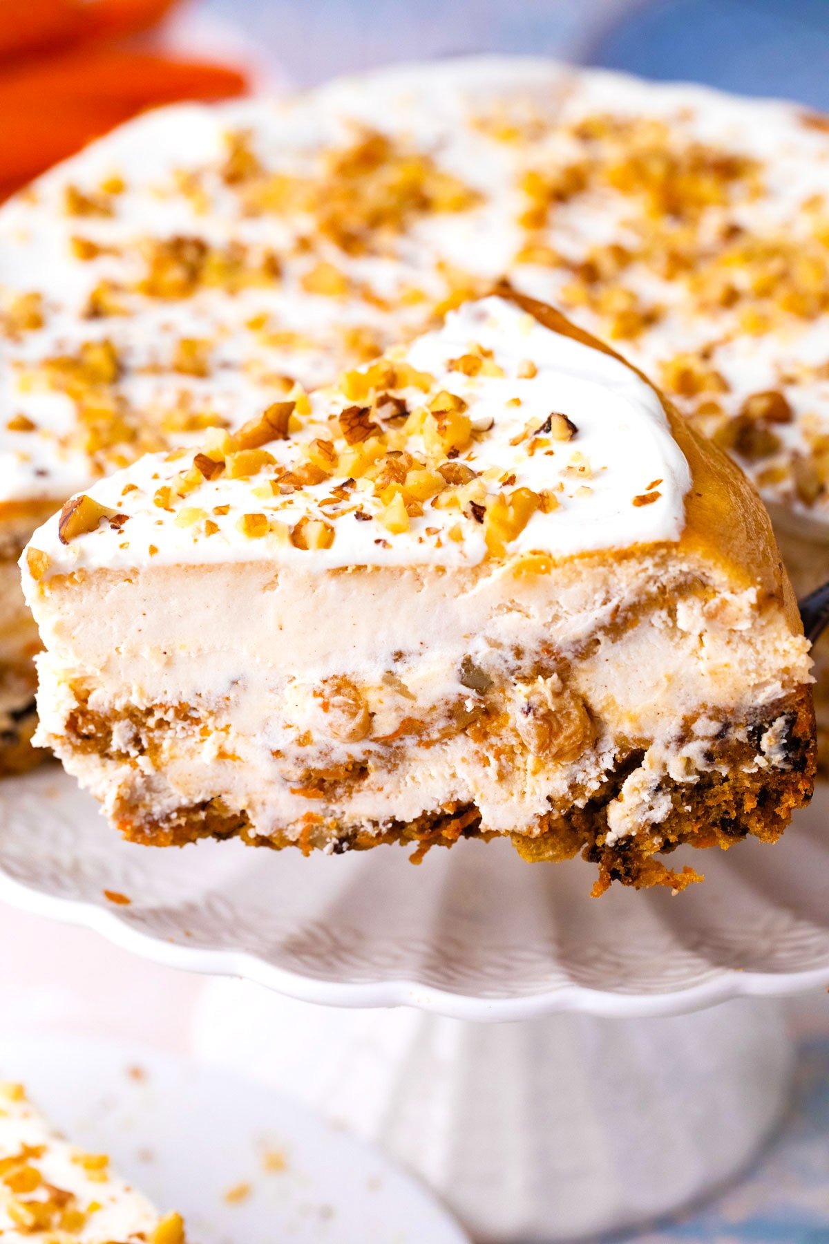 A slice of carrot cake cheesecake on a serving spatula.