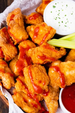 Crispy boneless chicken wings served with sauce, celery sticks. and carrots.