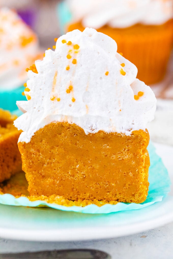 Sweet potato pie cupcake topped with whipped cream sliced in half.