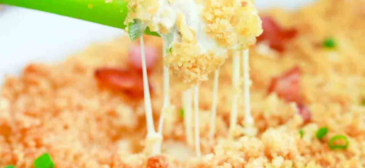 scooping jalapeno popper dip with a celery stick