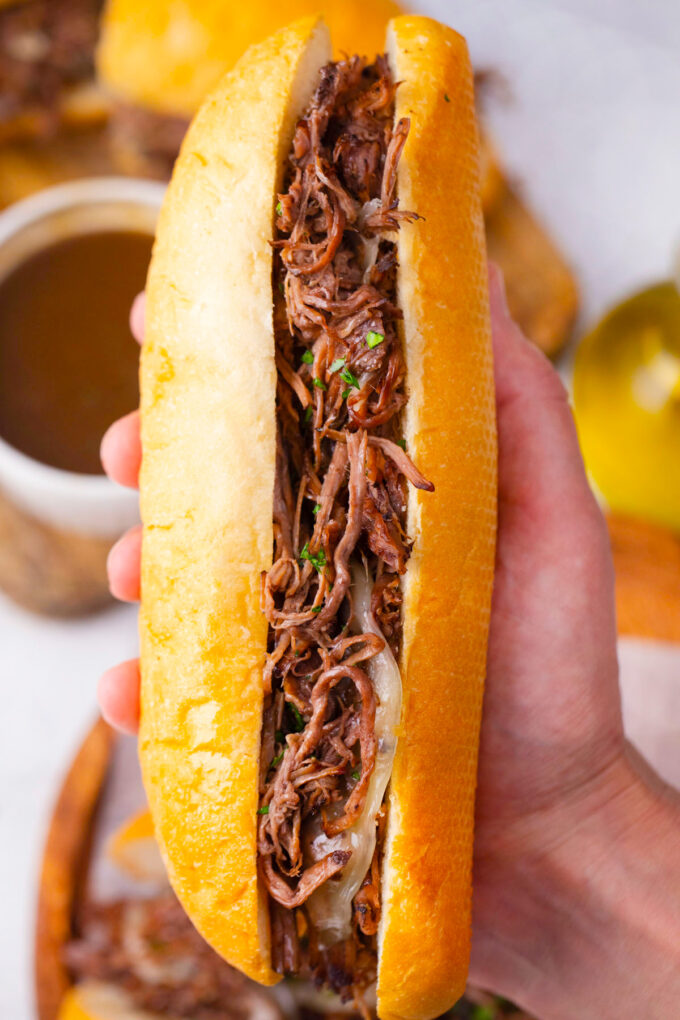 Holding a juicy and tender slow cooker French dip sandwich.