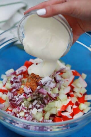adding salad dressing to a crab salad