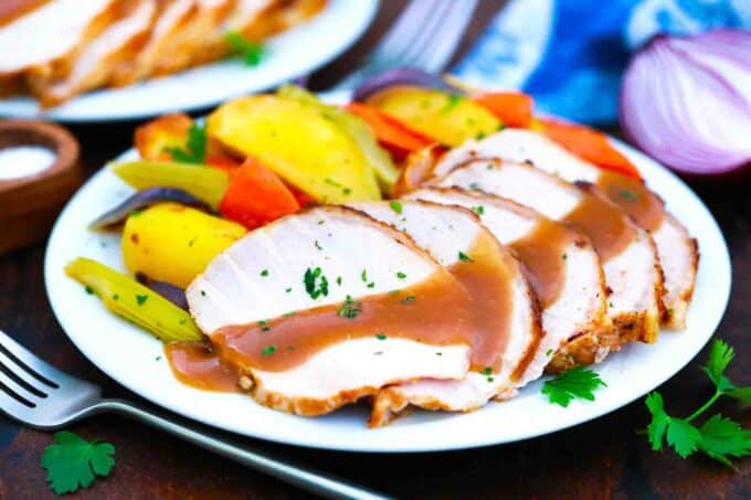 maple pork roast with apple cider gravy and veggies on a plate