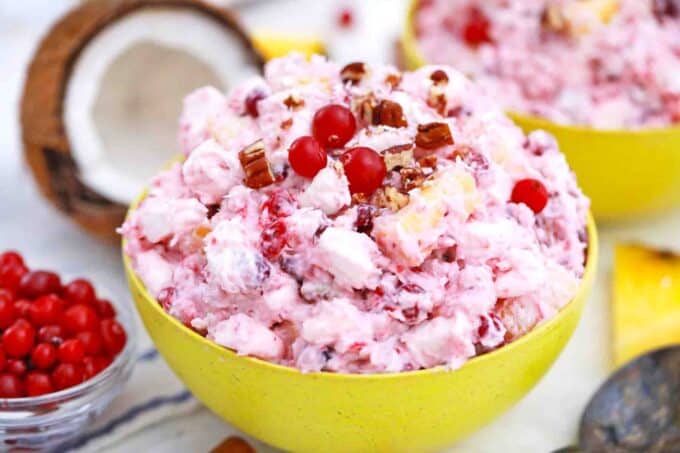 a bowl of mllionaire cranberry salad with a coconut in background