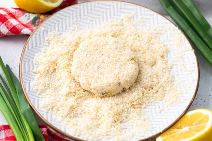 Coating a crab cake in panko breadcrumbs.