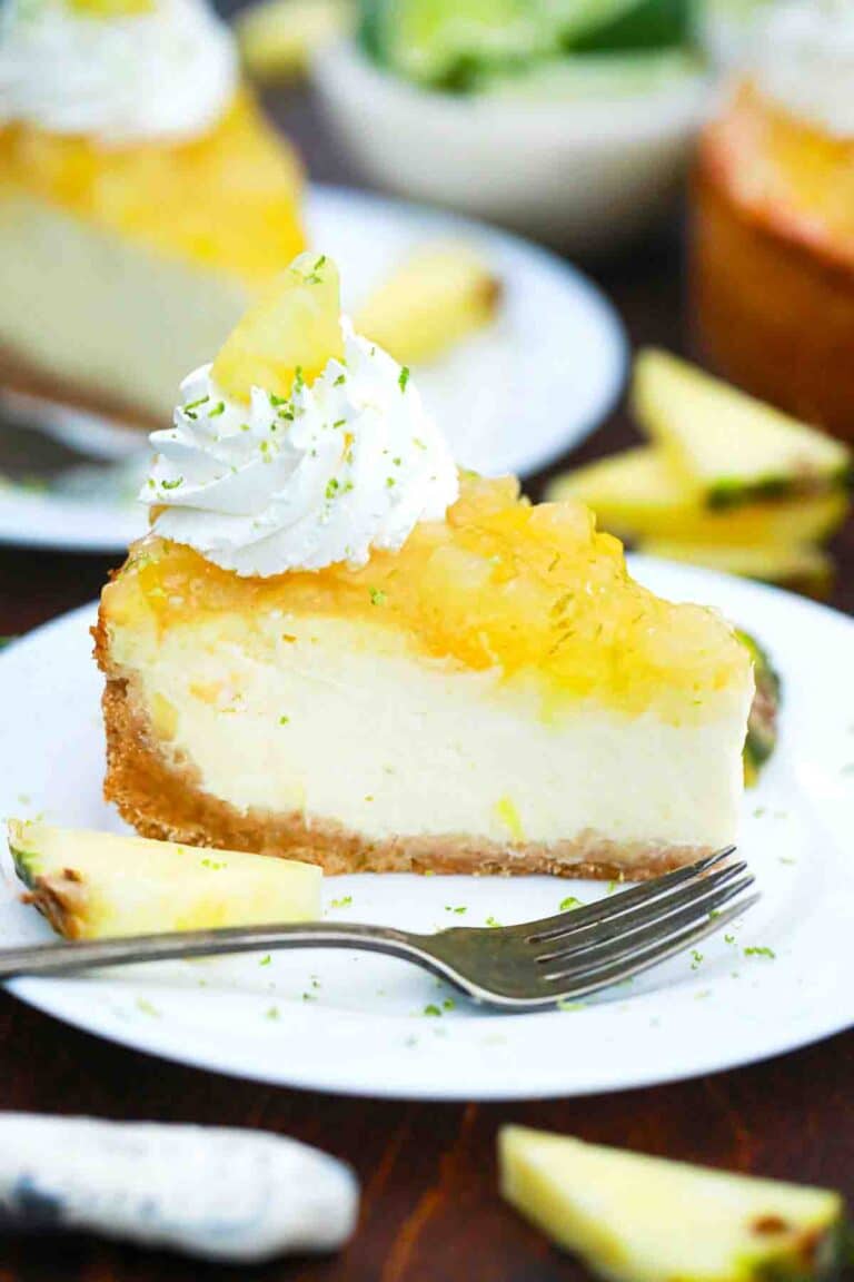 pineapple cheesecake slice with pineapple topping and garnished with whipped cream