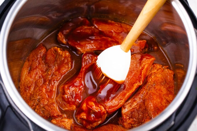 Adding BBQ sauce to Instant Pot country style ribs.