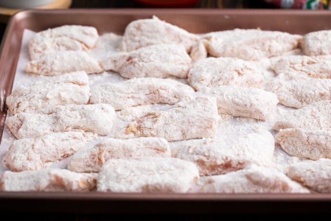 Raw crispy boneless chicken wings on a baking sheet.