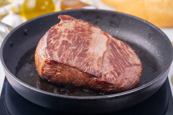 Searing beef chuck in a pan.
