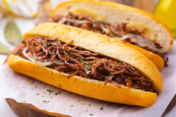 Homemade slow cooker French dip sandwiches on a cutting board.