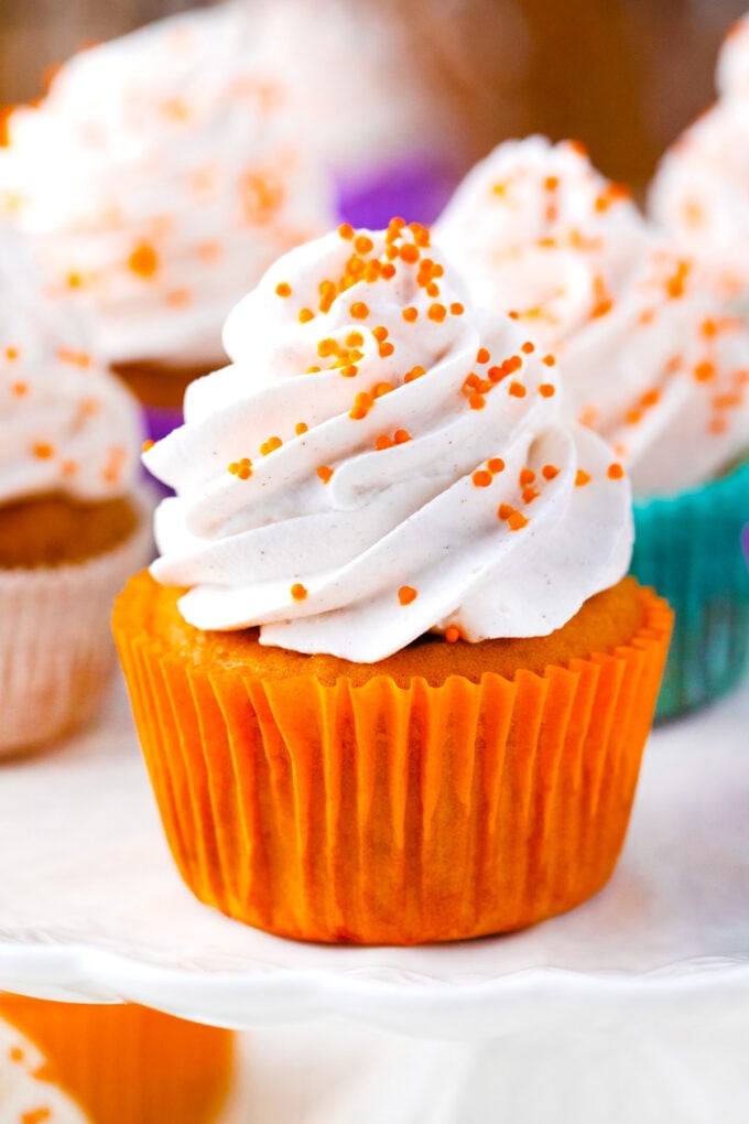 Sweet potato pie cupcakes topped with cinnamon whipped cream and orange sprinkles.