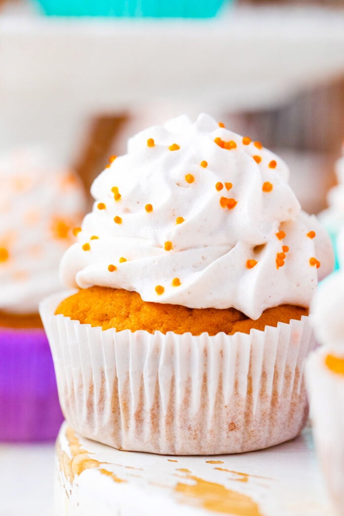Sweet potato pie cupcake topped with whipped cream and orange sprinkles.