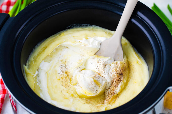 Stirring sour cream into slow cooker mashed potatoes.