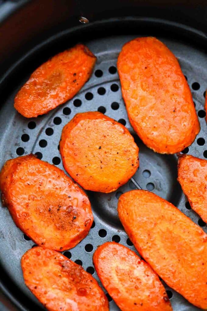 overhead shot of carrot slices cooking in an air fryer basket