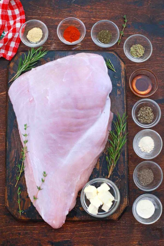 overhead shot of turkey breast, spices, maple syrup, butter and herbs on a table