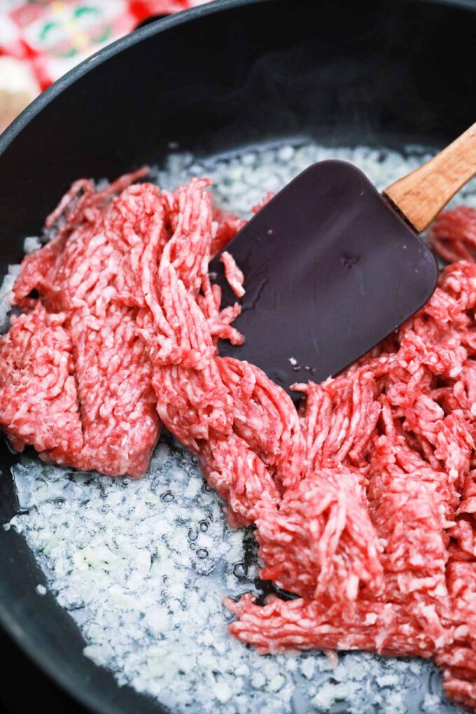 Cooking ground beef and minced onions in a pan.