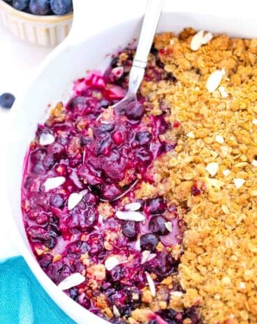close shot of blueberry crisp with a serving spoon