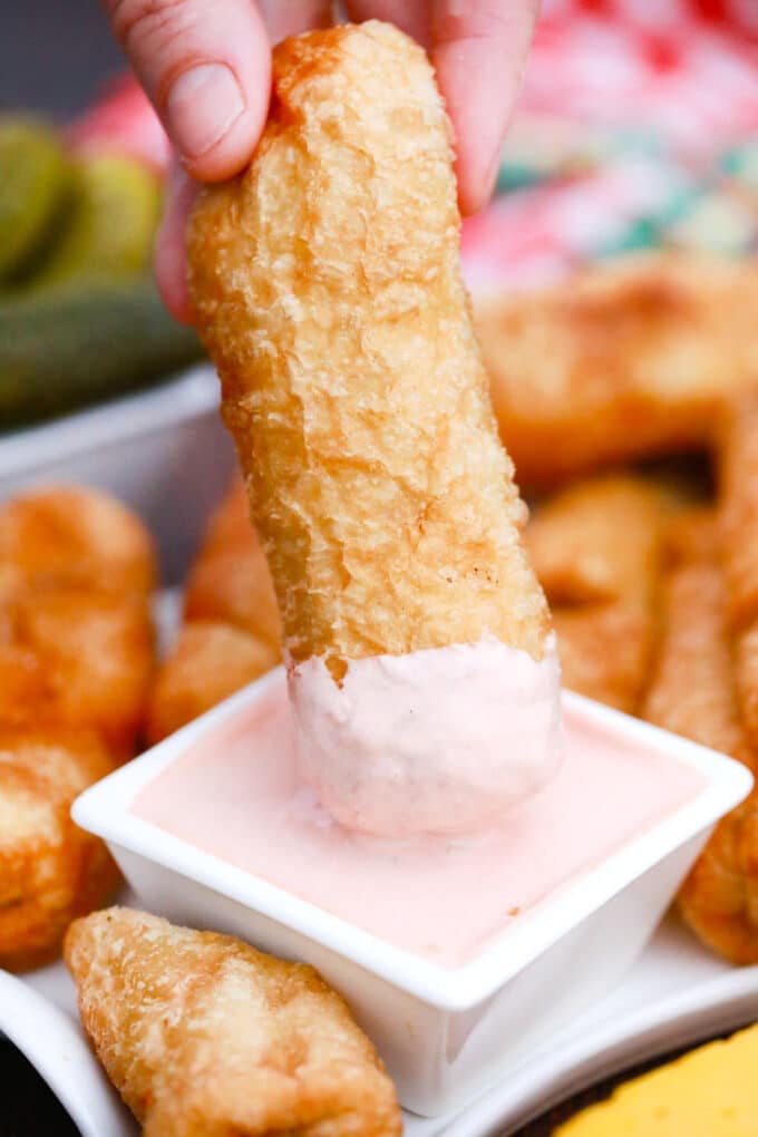 Dipping a cheeseburger egg roll into a creamy sauce.