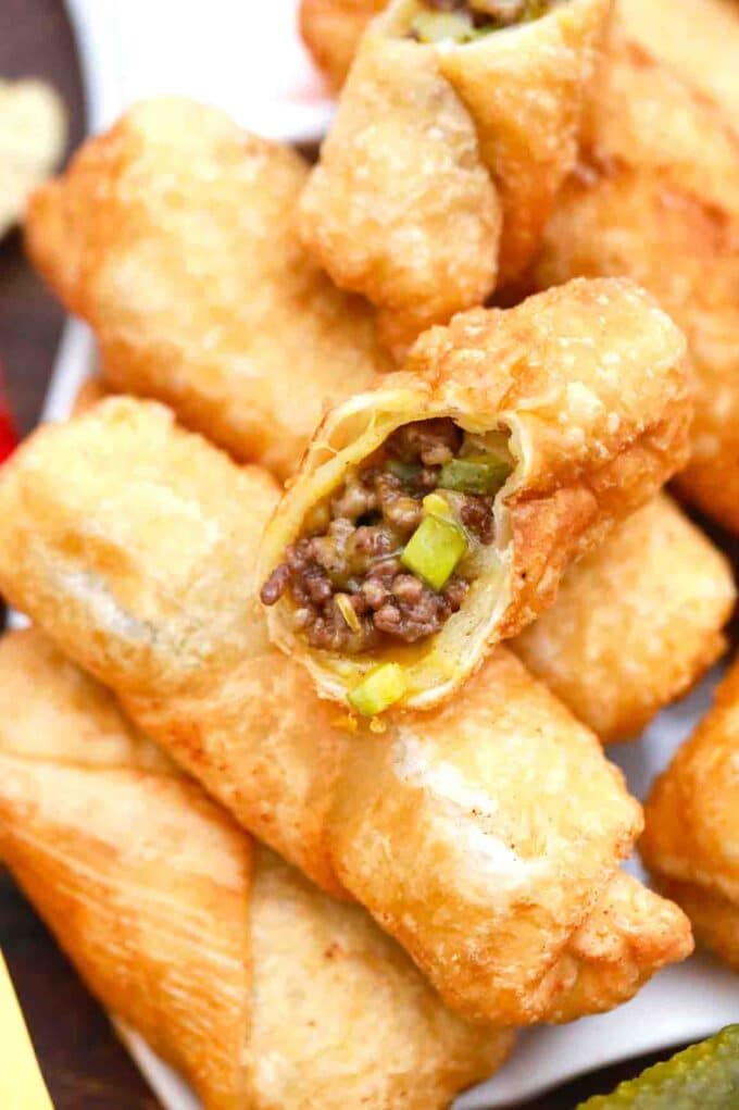 close shot of cheeseburger egg rolls on sliced in half revealing the cheesy beef filling