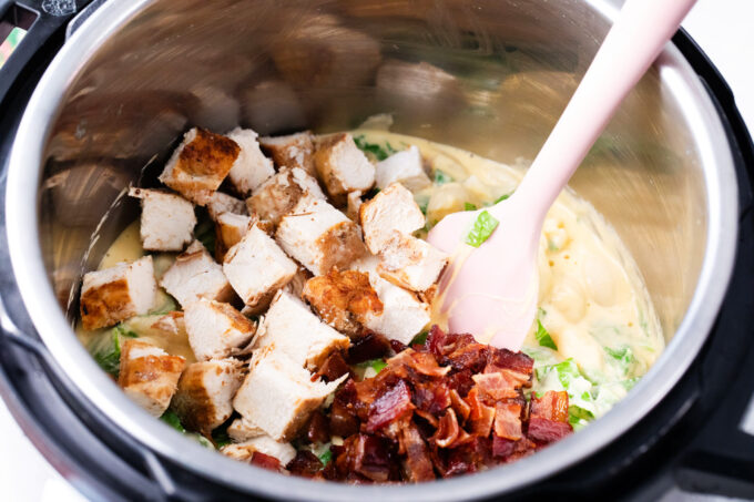 Mixing chicken and bacon pieces into cheesy instant pot chicken bacon ranch pasta.