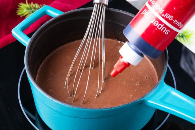 Adding red gel food coloring to hot cocolate.
