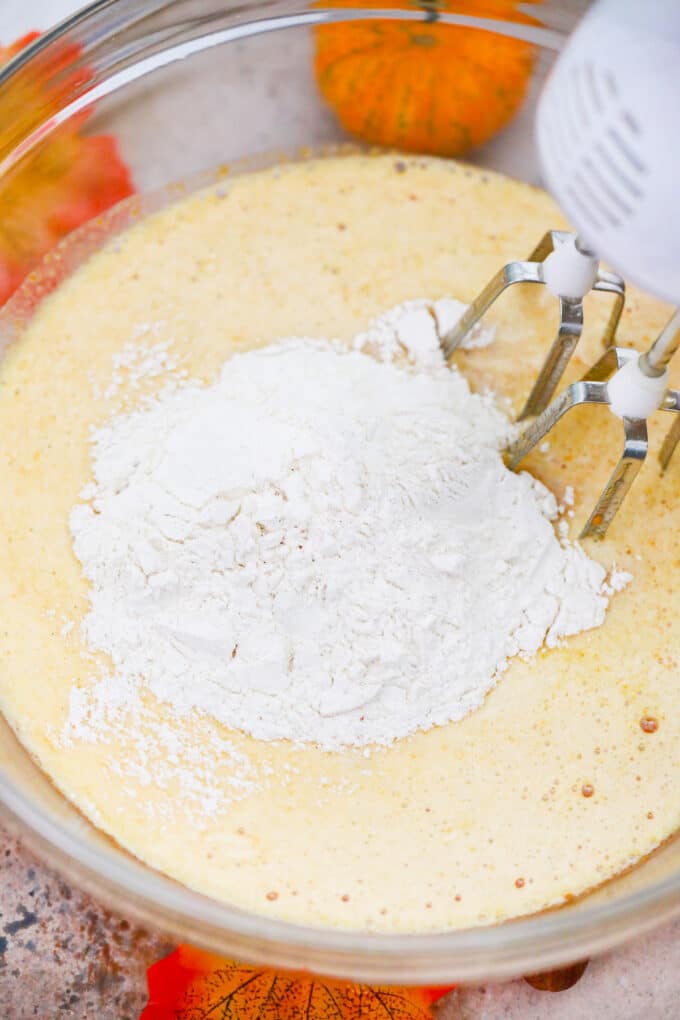 Mixing dry ingredients into wet ingredients for pumpkin cake.
