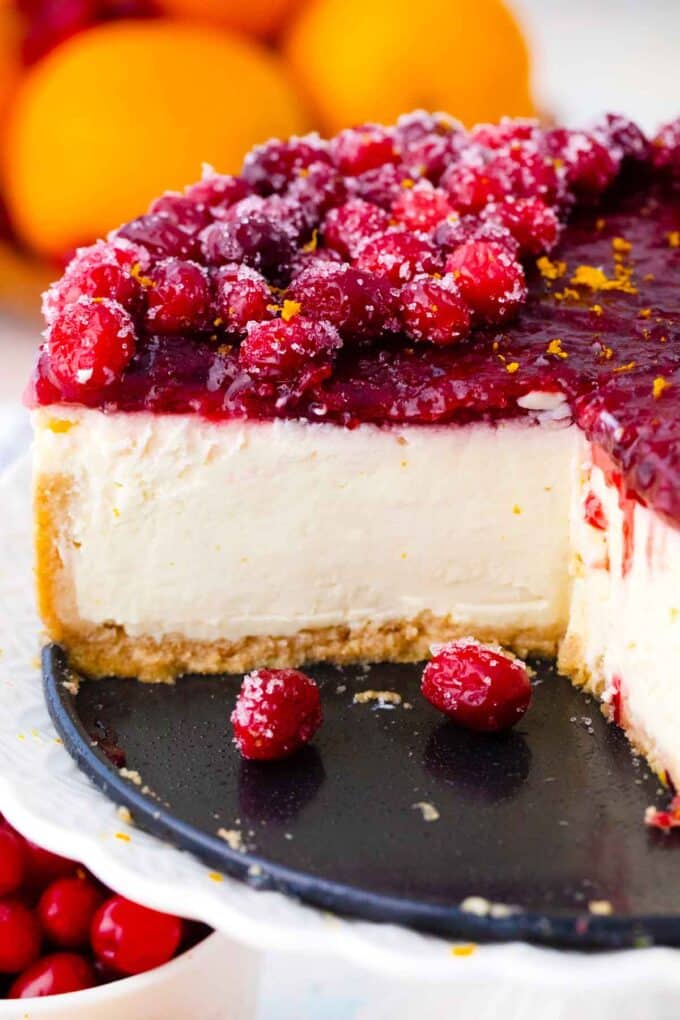 sliced cranberry cheesecake topped with cranberry sauce and sugared cranberries