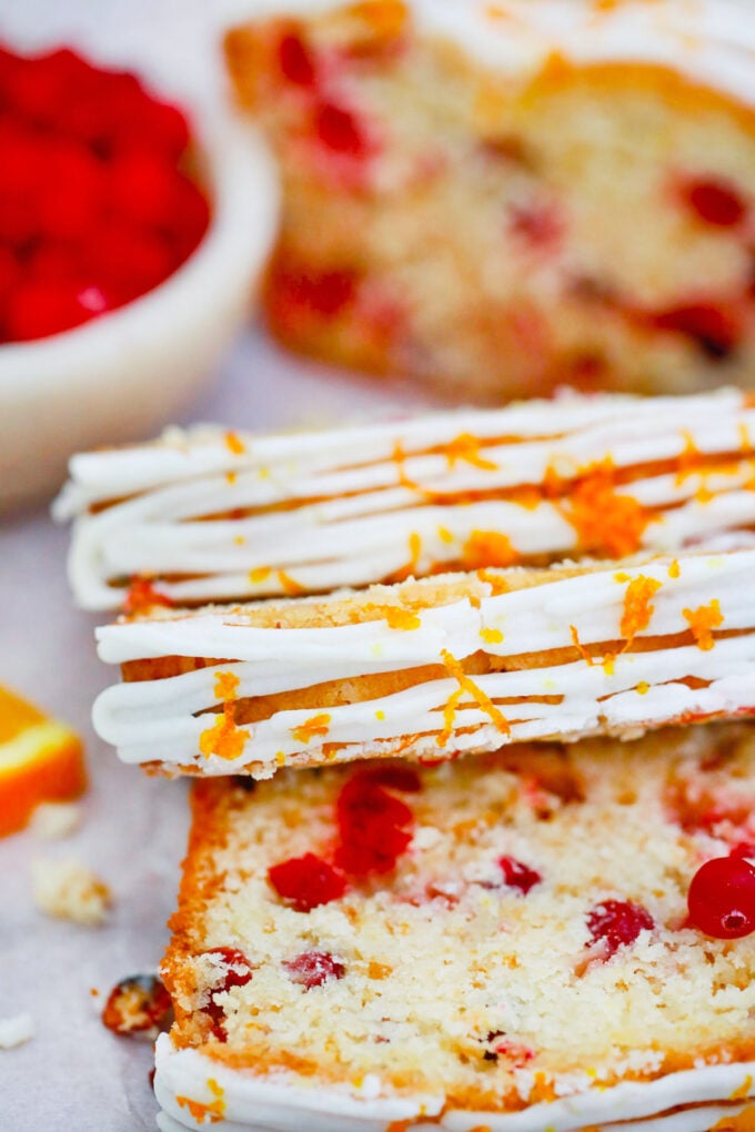 Slices of cranberry orange bread topped with orange glaze and orange zest.