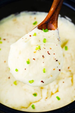 A serving spoon of very creamy slow cooker mashed potatoes